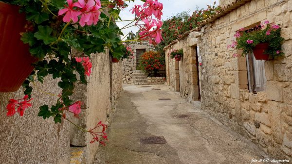 Vicoli di Buscemi, un borgo in pietra con fioriture di gerani.