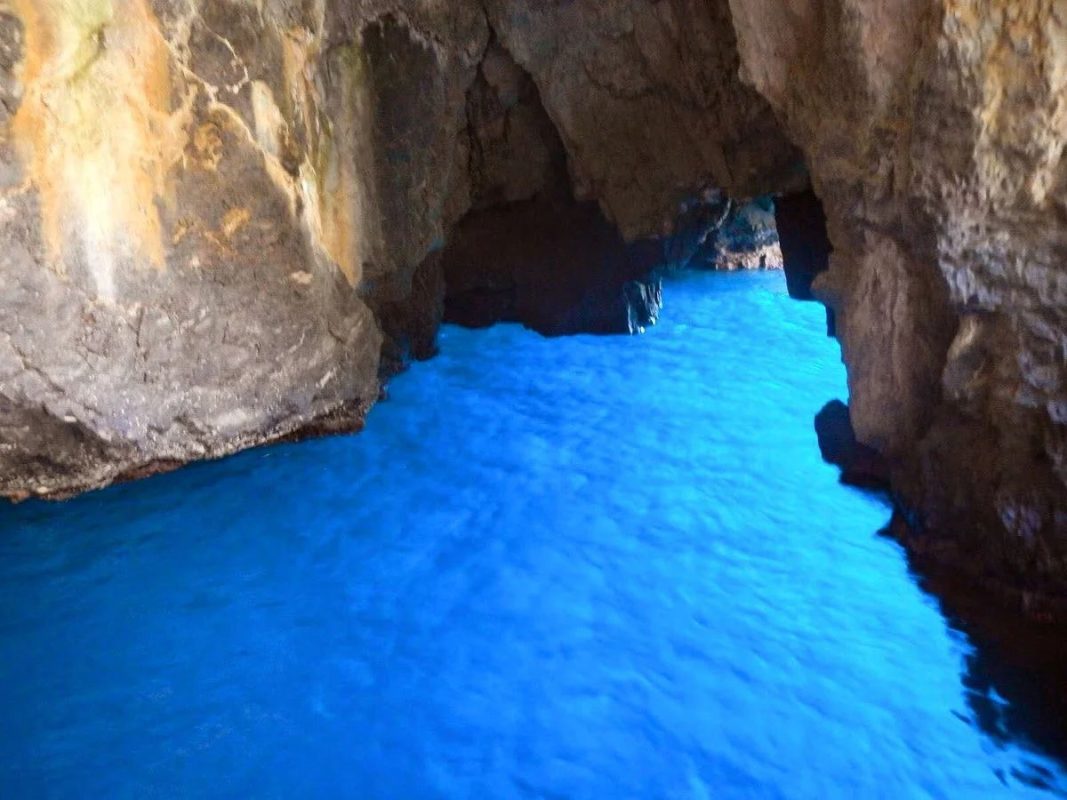 Interno della Grotta Azzurra di Taormina con acqua cristallina di colore azzurro intenso e pareti rocciose naturali.