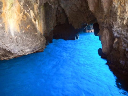 Interno della Grotta Azzurra di Taormina con acqua cristallina di colore azzurro intenso e pareti rocciose naturali.
